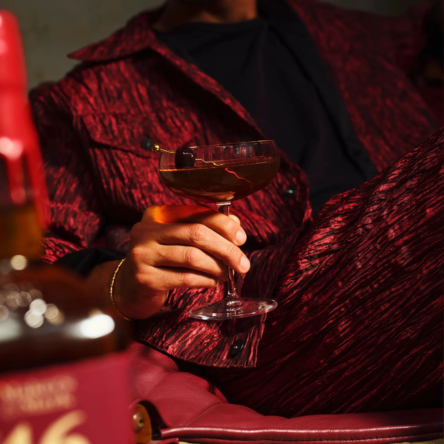 Manhatten bottle image and hand holding glass